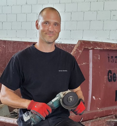 Das Team von Gerster Recycling bietet einen zuverlässigen Serivce. Im Hintergrund ist der Familienbetrieb und grosse rote Abfallcontainer mit dem Logo von Gerster Recycling zu sehen. Das Bild zeigt kompetente Fachpersonen.