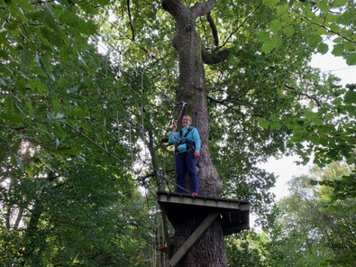 Susanne McCabe pauses and smiles for the camera on a platform on the treetop course.