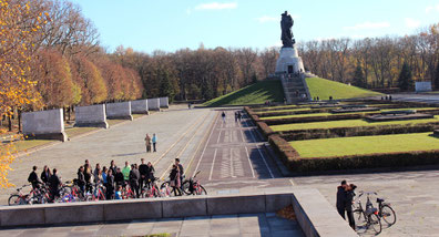 © Helga Karl. Sowjetisches Ehrenmal Treptower Park; Eine Gruppe Radfahrer, eine Touristenführung, Blick zum Hügel mit dem Rotarmisten mit Kind.