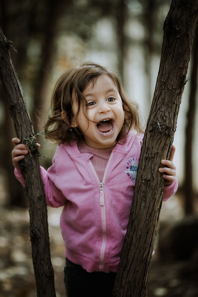 Petite fille qui rit entre deux arbres en pleine nature