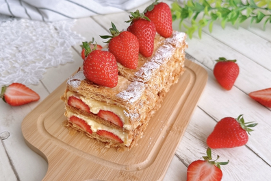 カッティングボードにミルフィーユケーキ。いちごがたくさんあしらわれている。