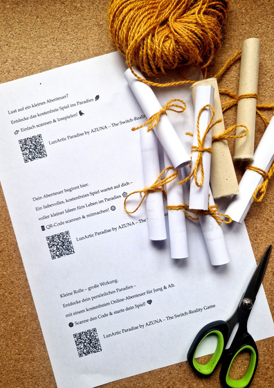 Selbstgemachte Mini-Schriftrollen für das Switch-Reality-Game, liebevoll aus Papier geschnitten, zusammengerollt und mit gelber Kordel gebunden. Daneben: eine Schere, gelbe Wollrolle und ein ausgedrucktes A4-Blatt mit QR-Codes und kurzen Texten.