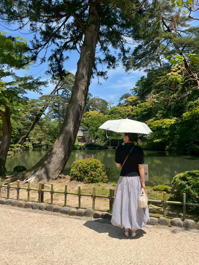 石川県金沢市にある日本三大名園の一つ、兼六園にて日傘をさした女性がCargo Shipオリジナルの横長ボストンバッグducksアイボリーを手にもち、庭を眺めてます。