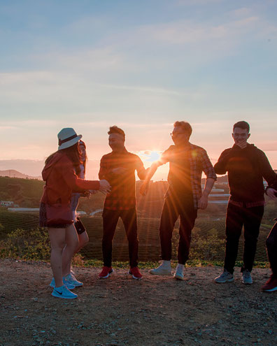 5-6 Jugendliche stehen beim Sonnenuntergang zusammen und haben gute Laune