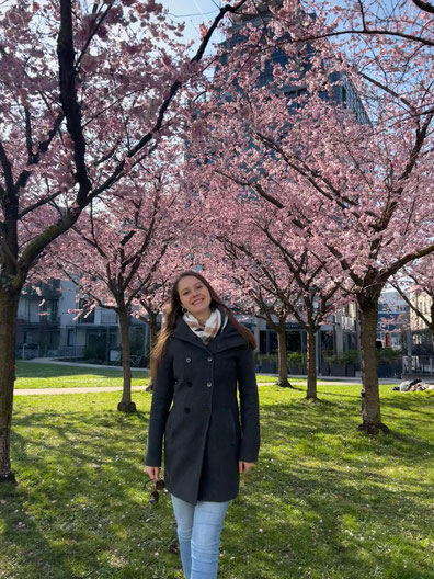 Portraitfoto von Jolina Hukemann in Bluse vor grüner Hecke.