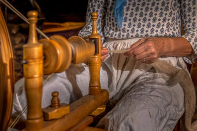 Reportage photographique du métier de tisseur - Myriam tisse la laine sur une ancien rouet