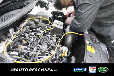 Bild zeigt Mechaniker beim Einbau eines Marderschutzes im Motorraum eines KFZ