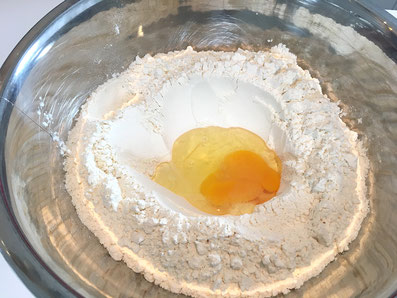 Mit dem Mehl einen Krater bilden und das Ei rein geben