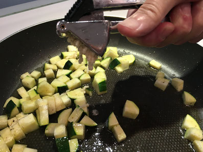 Den Knoblauch über die Zucchini pressen