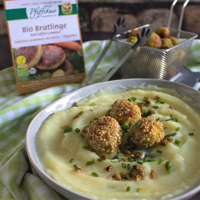 Vordergrund: kleines silbernes Frittier Sieb mit kleinen, angebratenen Klößchen, im Hintergrund: grauer Teller mit heller Suppe und Klößchen auf einer grünen Tischdecke. Rezeptfoto 2