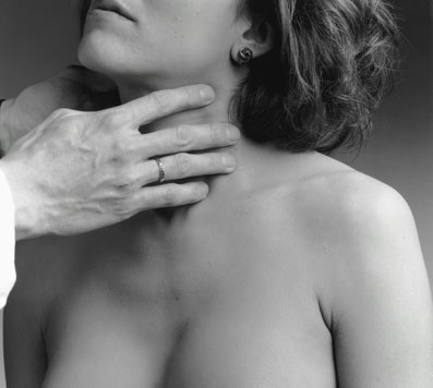 Eine Ärztin legt ihre beiden Hände um den Hals einer Frau und tastet ihn ab