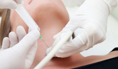 Ärztin mit Handschuhen führt feine Sonde unter Ultraschallkontrolle am Hals einer Patientin ein