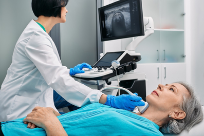 Ärztin untersucht die Schilddrüse einer Patientin mit einem Ultraschallgerät
