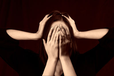 Eine Frau hält sich die Hände vor dem Gesicht, als ob sie von Verzweiflung überwältigt wird.
