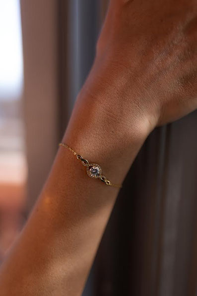 MOKOŠEV luxury jewelry, delicate gold bracelet with a sparkling crystal on a wrist in warm light.