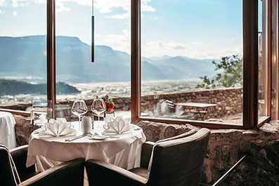 Elegant gedeckter Tisch im Restaurant Haselburg in Bozen mit Panoramablick über das Etschtal und die Südtiroler Berge – stilvolles Ambiente mit Aussicht und Genuss.