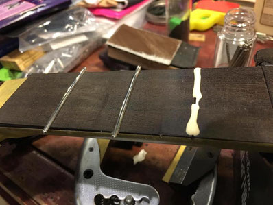 ギターのネックにステンレスのフレットをボンドで固定する作業