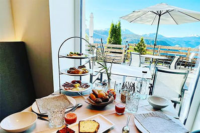 Reichhaltiges Frühstück mit regionalen Spezialitäten auf einer Etagere in Pippo's Mountain Lodge in Oberbozen mit Panoramablick auf die Südtiroler Berge