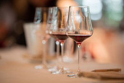 Diversi bicchieri di vino rosso sono disposti su un tavolo apparecchiato con tovaglie bianche alla Festa del Vino di Vigiljoch, nel ristorante 1500 del vigilius mountain resort a Lana, in Alto Adige.