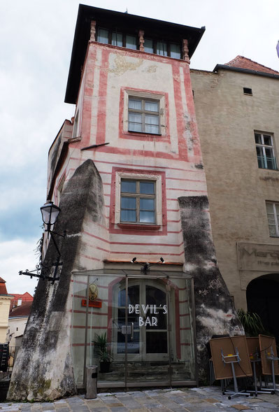 Die Fassade vor der Restaurierung mit Putzschäden durch aufsteigende Bodenfeuchtigkeit, abgewittertem Kalkanstrich und massivem Algenbefall.