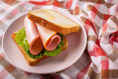 ハムとレタスのサンドイッチがのったお皿。チェック柄のクロス。