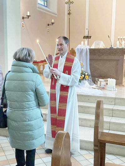 Foto zeigt eine Kirchgängerin, der Pfarrer Holger Schmitz den Blasiussegen spendet