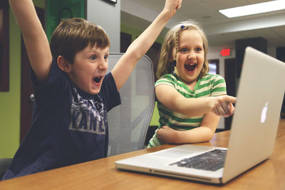 2 Kinder jubelnd vor einem Laptop