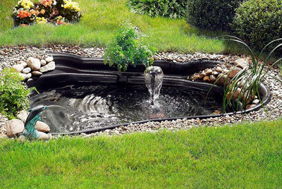 Fertigteich mit Brunnen Wasserpflanzen und Kieselsteinen