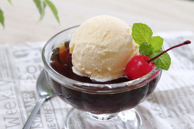 アイスクリームがのったコーヒーゼリーのガラスの器。ミントの葉とサクランボが添えられている。