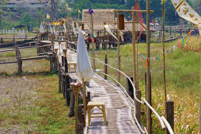 Dans la région de Lampang, on peut marcher sur un pont en bambous qui surplombe les rizières et mène à un temple