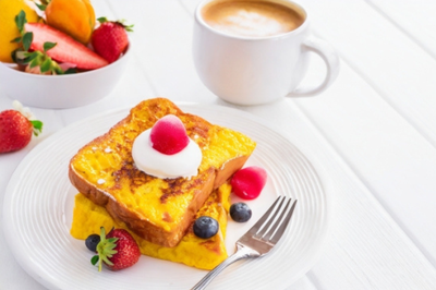 クリームとフルーツが添えられたフレンチトーストのお皿。カフェラテのマグカップ。
