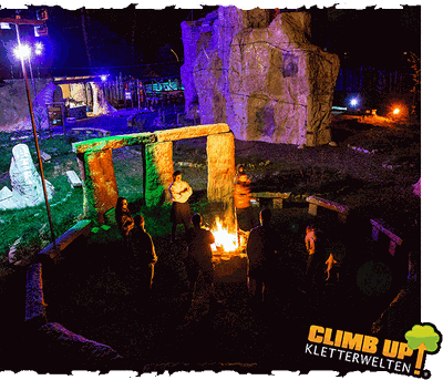 CLIMB UP! – Bergwelt Strausberg: Gäste am Lagerfeuer vor dem Kletterfelsen, stimmungsvolle Beleuchtung in der Outdoor-Eventlocation.