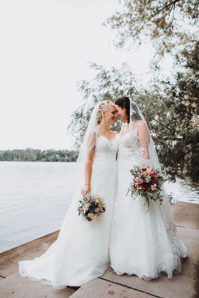 Regenbogenhochzeit mit zwei Bräuten in weißen Brautkleidern