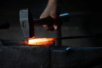 Ein Hammer trifft auf ein glühendes Metallstück