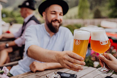 Der Musikantenstammtisch im Brauhaus Martinerhof in Passeier im Braubereich der Brauerei. Ein Musikant mti einem Bier im Freien.