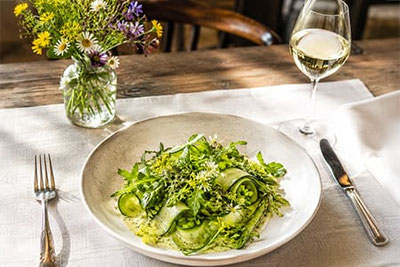 Piatto estivo leggero delle locande dell'Alto Adige con insalata verde, asparagi, erbe aromatiche e vino bianco – gusto della rassegna Sommerfrische. 
