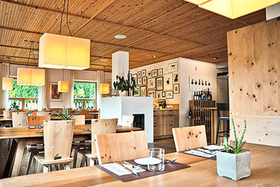 Moderner Gastraum im Restaurant Binderstube in Völs mit Holzmöbeln, warmem Licht, gedeckten Tischen und stilvoller, gemütlicher Atmosphäre.