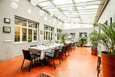 Condito Bozen Eventlocation mit stilvollem Innenraum, gedeckter Tafel, Glasdach und hängenden Lampions – modernes Ambiente für Feiern und kulinarische Events