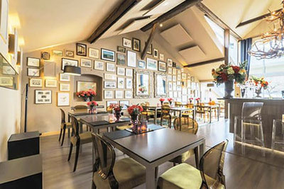 Arôme Restaurant & Café in Bozen: stilvolles Ambiente mit Galerie-Wänden, eleganten Tischen, Blumendeko, moderner Bar und gemütlicher Beleuchtung
