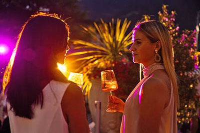 Due donne si godono un aperitivo al tramonto durante il martedì sera a Merano, tra luci suggestive e atmosfera estiva.