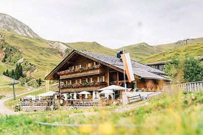 Die Kirchsteiger Alm bei Meran 2000 mit Sonnenterrasse, Blumenbalkon und Haflinger – umgeben von Bergwiesen und Gipfeln, ideal für Wanderer und Genießer.