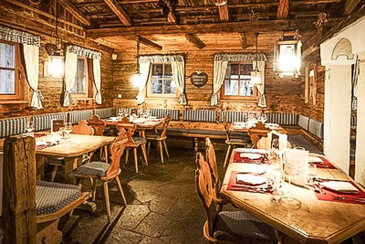 Stube tradizionale nel ristorante Jora Mountain Dining a San Candido con interni rustici in legno, tavoli apparecchiati, luci calde e un'accogliente atmosfera alpina.