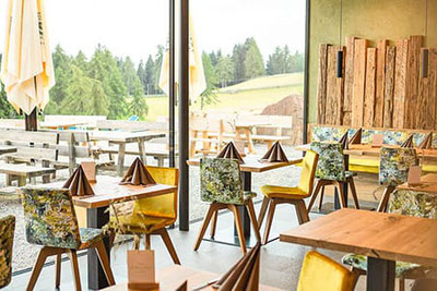 Moderne, gemütliche Einrichtung im Berggasthof Lanzenschuster in Jenesien, mit Blick auf die Weiten des Tschögglbergs und warmen, natürlichen Holztönen.