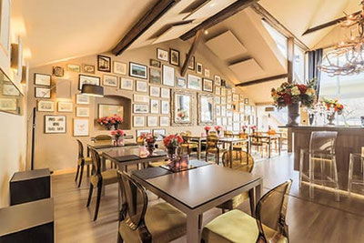 Arôme Ristorante & Caffè a Bolzano: ambiente raffinato con pareti a galleria, tavoli eleganti, decorazioni floreali, bar moderno e illuminazione accogliente