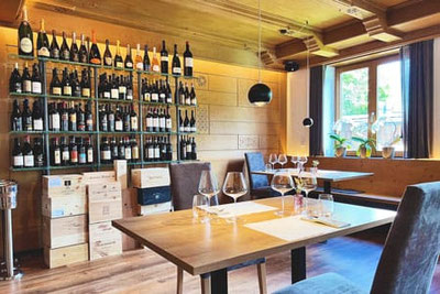 Steakhouse Anny a Marlengo con elegante parete dedicata ai vini, tavoli apparecchiati in stile moderno, caldi interni in legno e luminosi posti a sedere vicino alle finestre con orchidee: un ambiente elegante e piacevole.