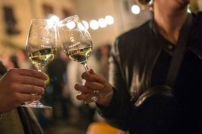 Zwei Besucher beim Traminer Weingassl in Tramin in Südtirol beim Anstoßen mit Weisswein