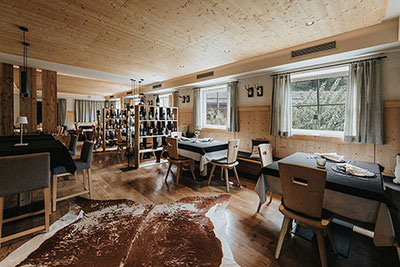 Blick in den lichtdurchfluteten Speisesaal im alpinen Stil des Restaurants Presulis in Völs am Schlern in Südtirol