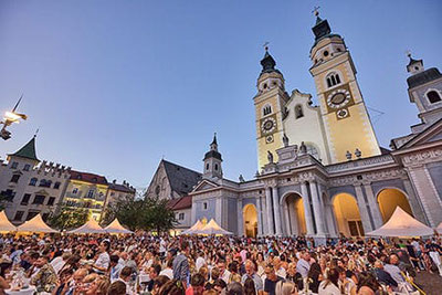 Großes Sommerfest bei Dine, Wine & Music am Domplatz in Brixen – zahlreiche Besucher genießen Essen, Wein und Livemusik vor der eindrucksvoll beleuchteten Domkulisse