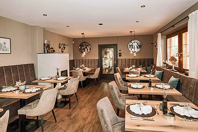 Sala da pranzo elegantemente apparecchiata nel ristorante Pichler a Scena con vista panoramica sulle montagne dell'Alto Adige: un ambiente raffinato per buongustai.