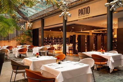 Eleganter Innenbereich des Restaurant Patio in Bozen mit modernem Design, gedeckten Tischen, Glaspyramide und warmer Atmosphäre im Sheraton